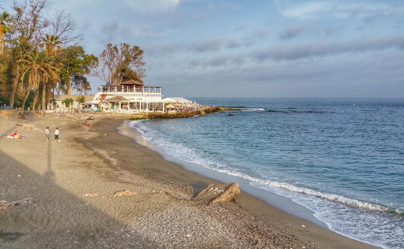 Wide view of Baños del Carmen at golden hour, with the historic restaurant pavilion on the rocky point and palm trees on the left