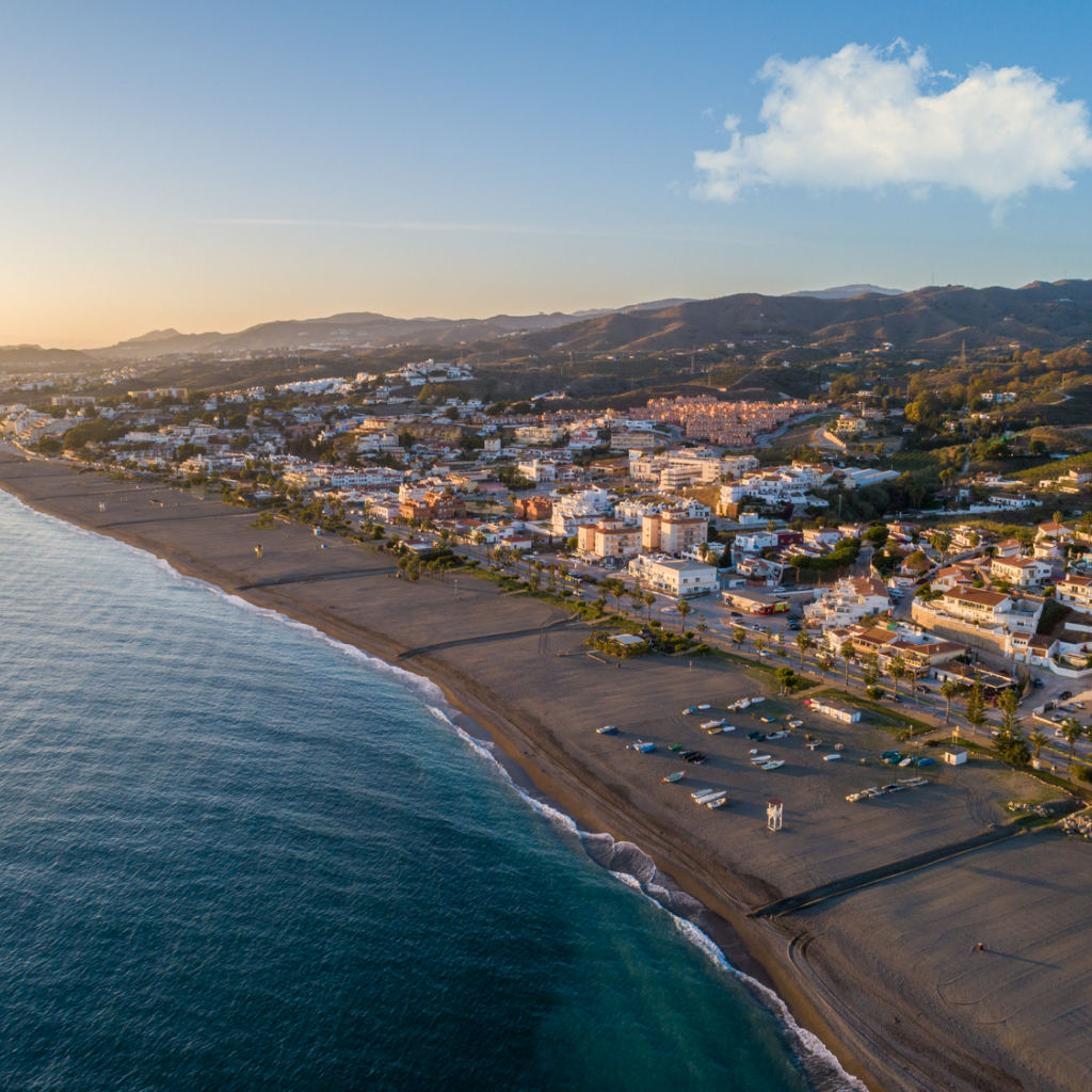 Aerial view of Playa de Benajarafe at sunrise, with the village and Axarquía hills behind